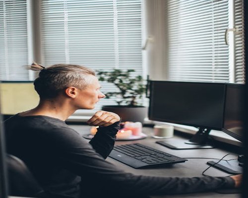 Person taking a break, looking away from their computer screen towards a window