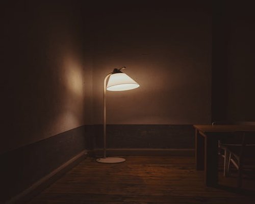 A dark room with a single soft lamp glowing, no screens visible